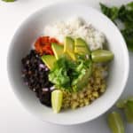 vegan burrito bowl in bowl with lime and avocado next to it