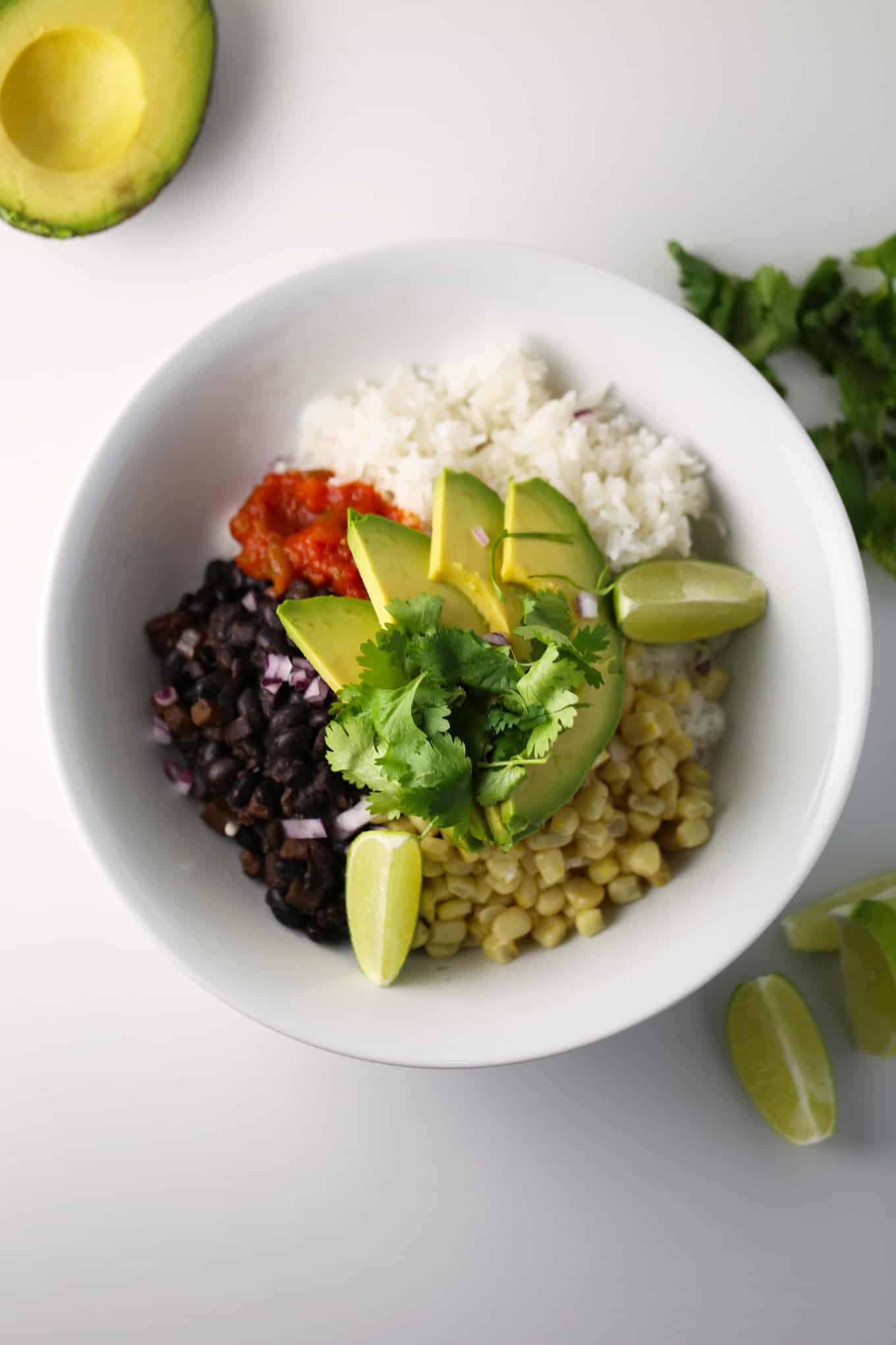 vegan burrito bowl in bowl with lime and avocado next to it