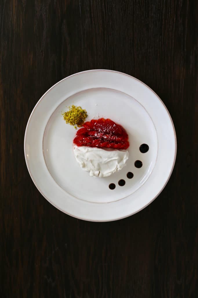 strawberries and coconut whipped cream with balsamic glaze, ground pistachio, and coconut flakes