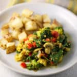 tofu scramble with vegetables on a plate with roasted potatoes