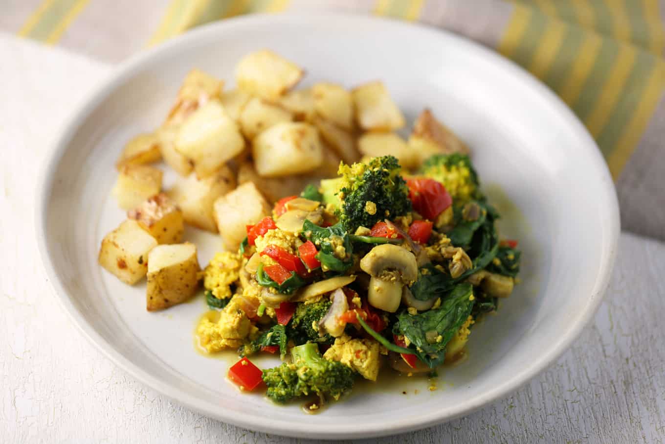 tofu scramble with vegetables on a plate with roasted potatoes