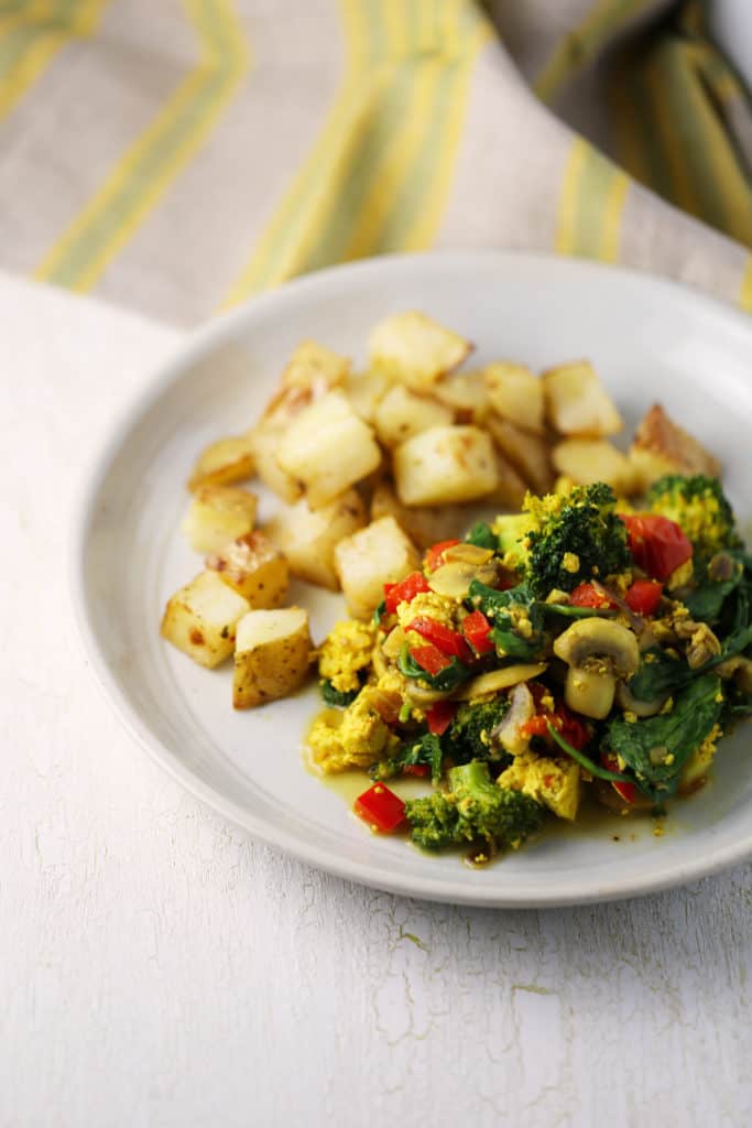 tofu scramble with veggies on a plate with roasted potatoes