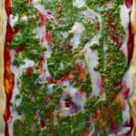 vegan mozzarella on top of pizza with tomato sauce and basil pesto