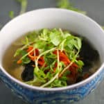 vegan miso soup in a bowl with sushi rice, pea shoots, and grated carrots