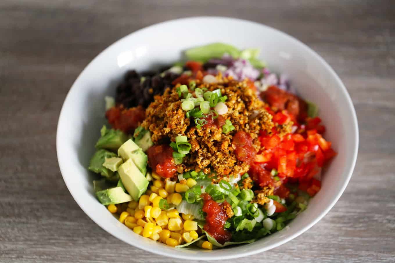 A bowl of vegan taco meat and an array of delicious fresh vegetables.