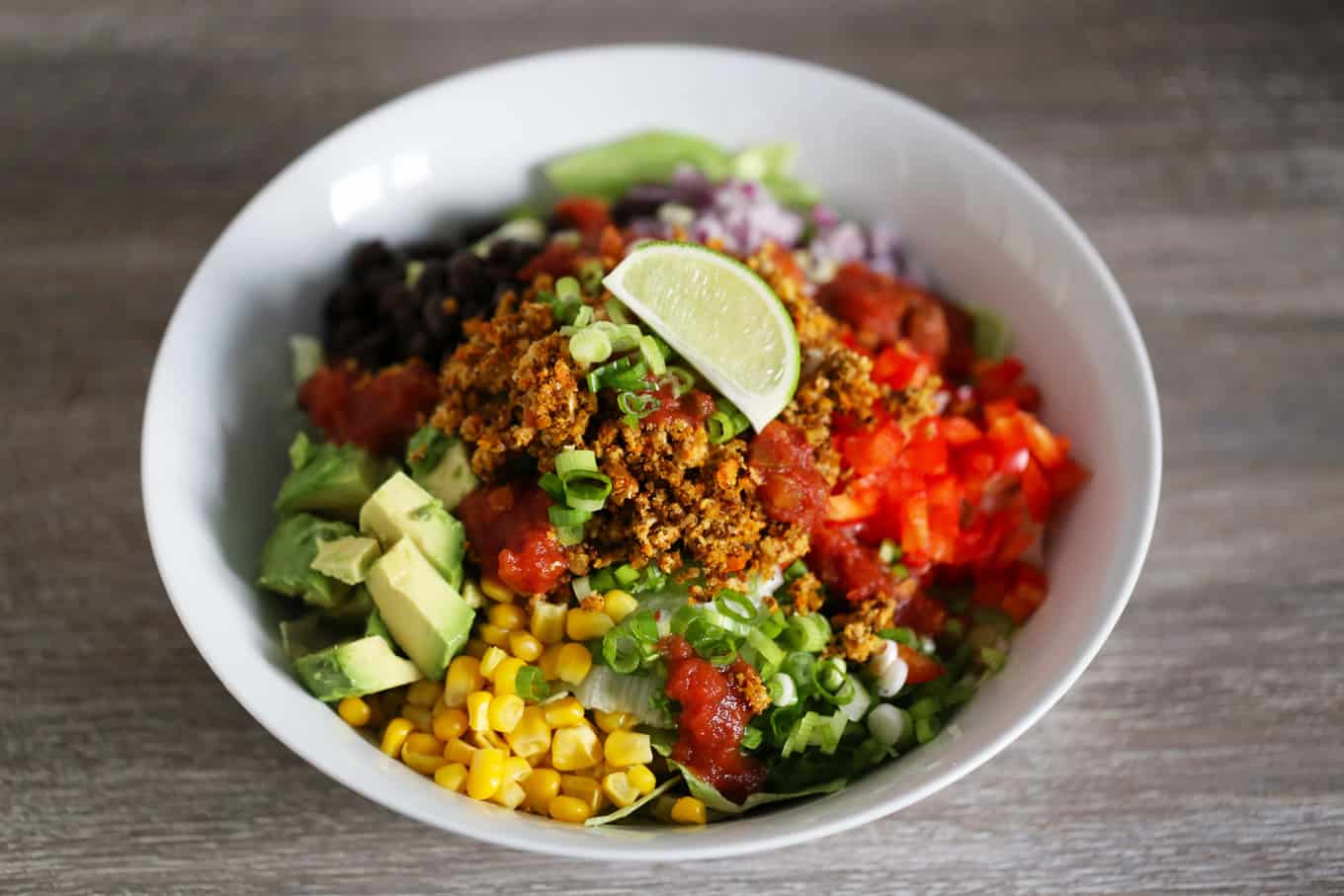 A vegan taco salad bowl, with vegan taco meat and fresh vegetables.