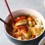 A bowl of Japanese Udon Noodles with tofu and a kimchi miso broth, with chopsticks.