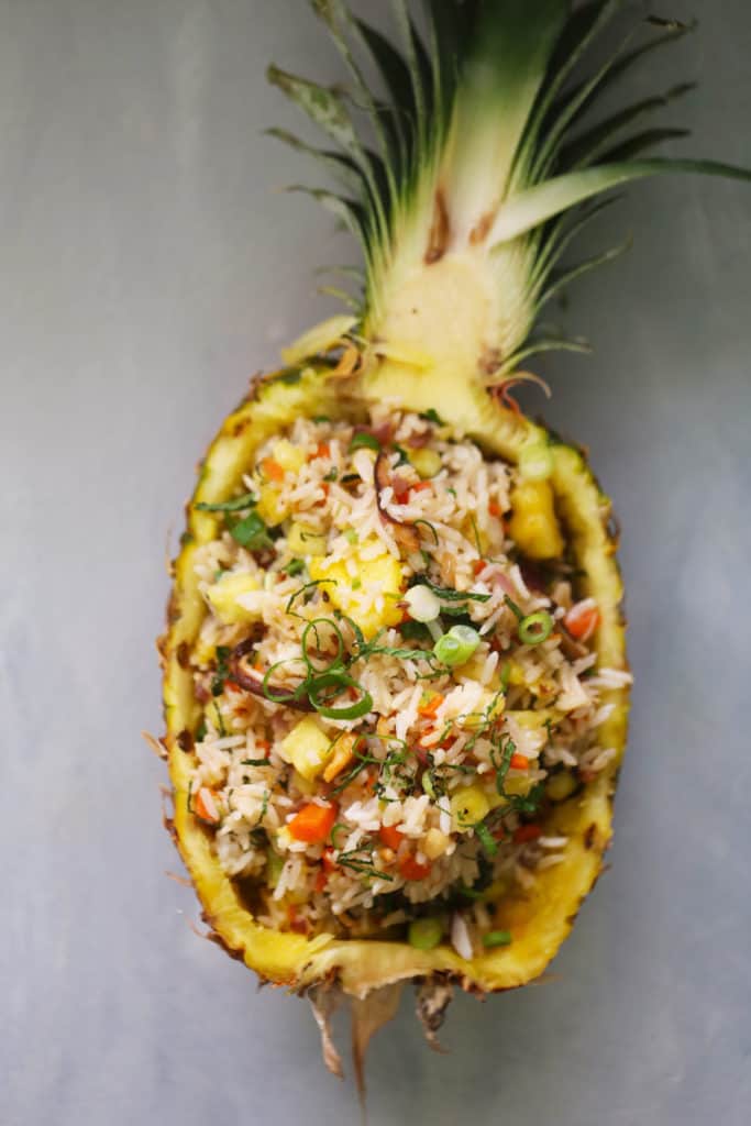fried rice with pineapple served in a hollowed out half pineapple