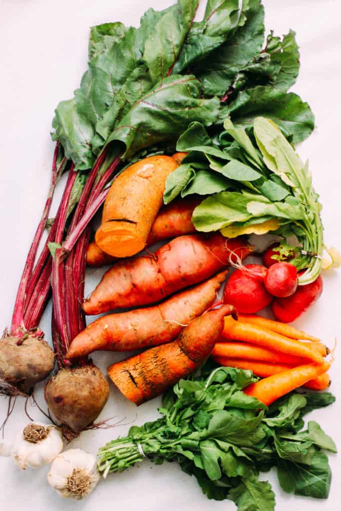 beets, carrots, radishes, garlic, and sweet potatoes on a table